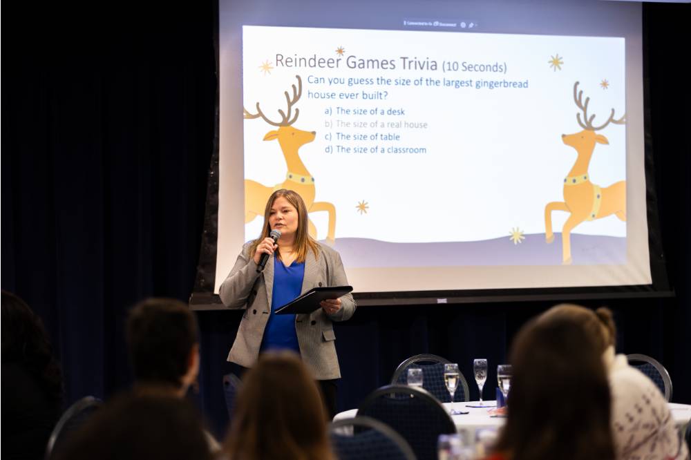 A presentation happening where the women is talking and there are reindeer on the screen behind her